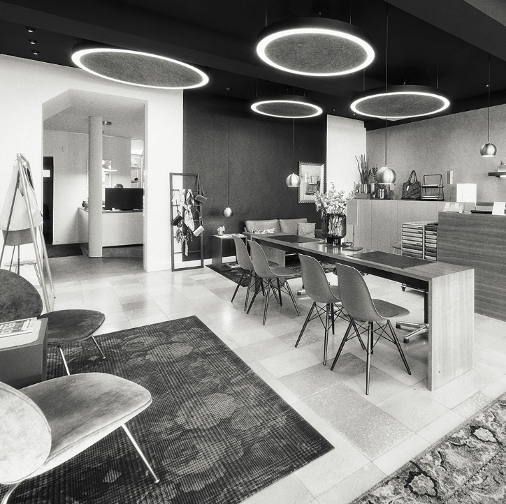 Modernes Büro mit großen runden Deckenleuchten, einem langen Tisch, Stühlen und einem Empfangsbereich. Büro im minimalistischen Stil.